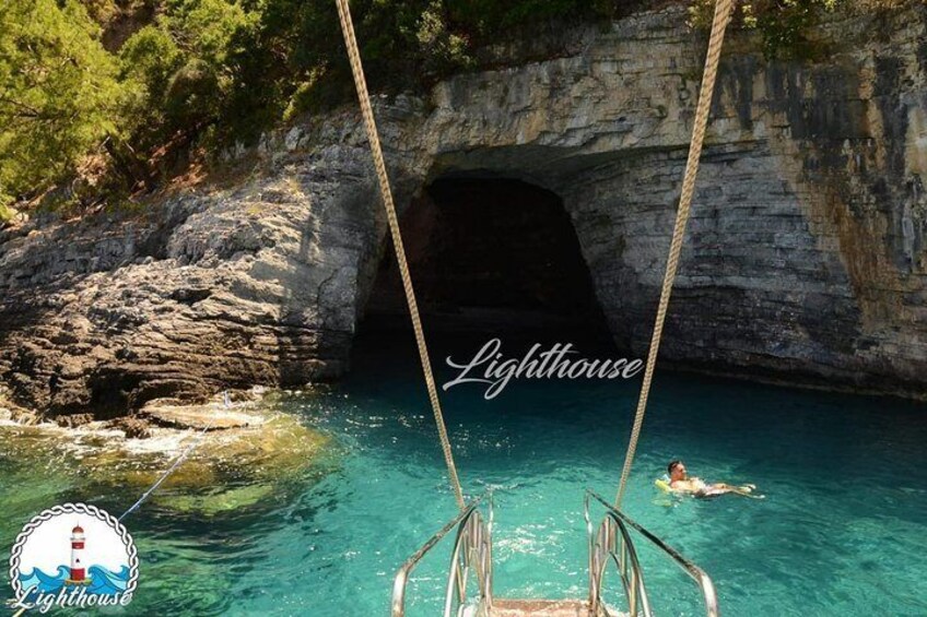 A rope swing over clear blue water with a rocky cave in the background. 4