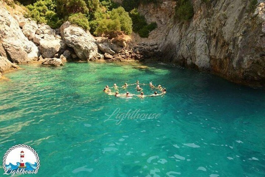 A group of people swimming in a clear blue pool surrounded by rocky cliffs. 2