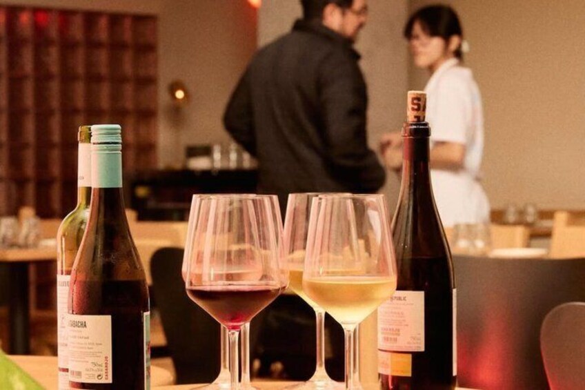 A table with wine bottles and glasses, a corkscrew, and a menu. 4