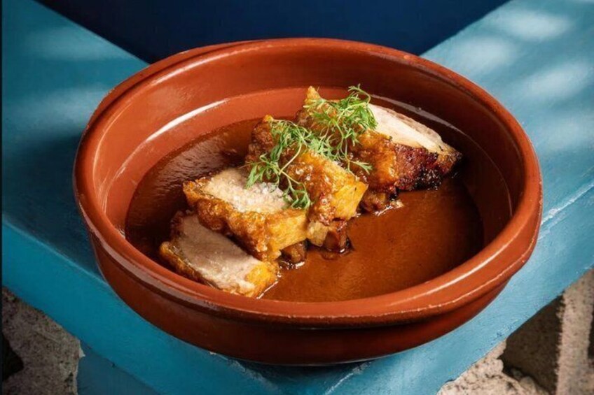 A terracotta bowl with sliced meat and herbs. 1