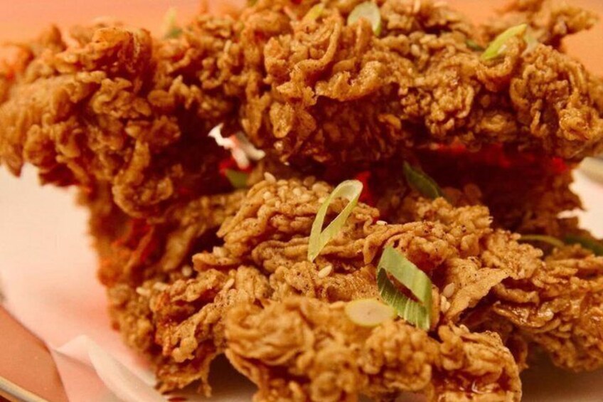 A close-up of crispy fried chicken pieces garnished with green onions. 3