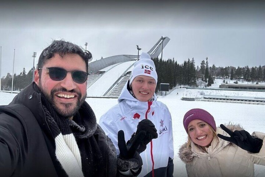 Three people in winter clothing, a snowy landscape, and a large structure in the background. 4