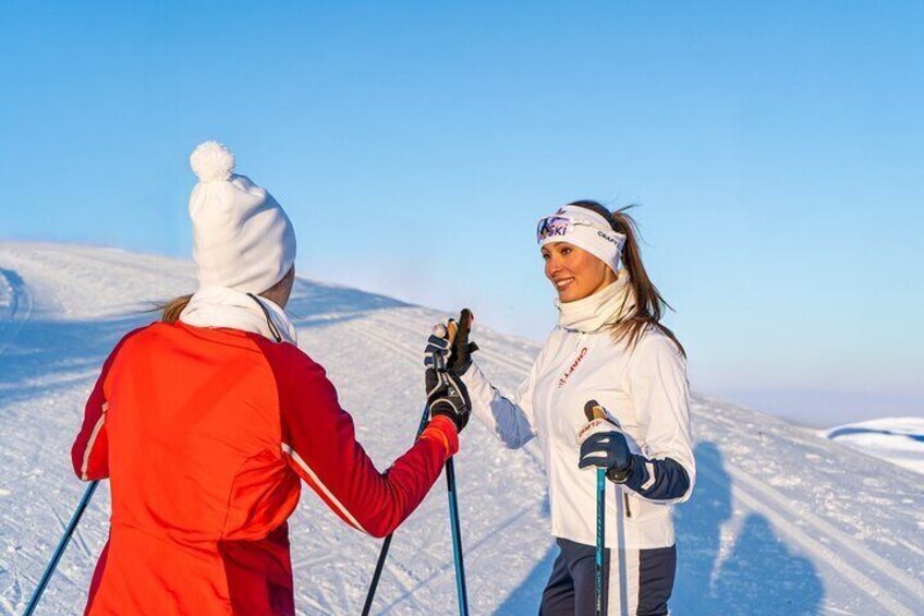 Two people skiing on a snowy mountain with clear skies. 1