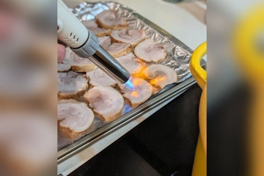 Slices of meat being grilled on a foil tray. 3