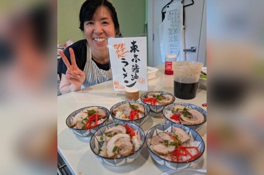 A person at a table with bowls of food, a sign with Japanese characters, and a cup of tea. 1