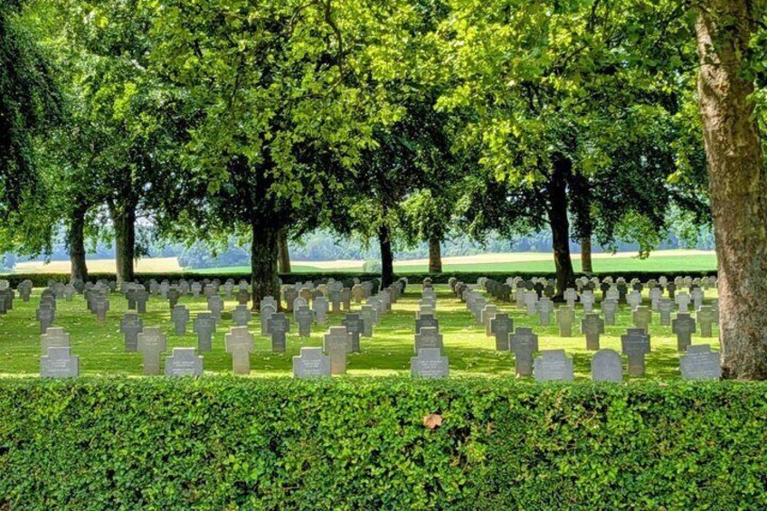 A cemetery with numerous headstones, surrounded by lush green trees. 2
