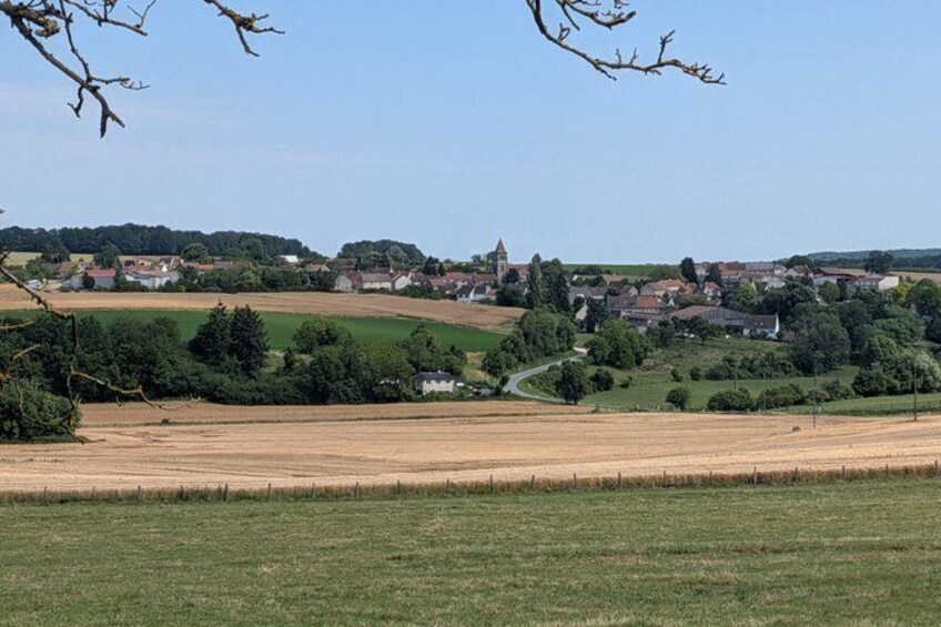 A rural landscape with fields, a village, and a church tower. 4