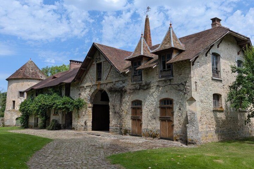 A historic stone building with multiple gabled roofs and a cobblestone pathway leading to the entrance. 5