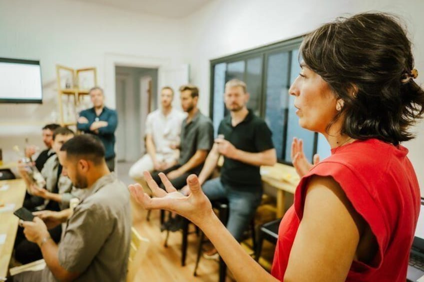 A person speaking to a group in a room with tables and chairs. 3