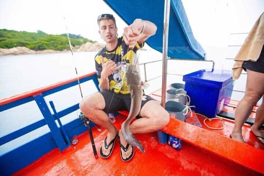 A person holding a fish on a boat with a blue railing and a red deck. 1