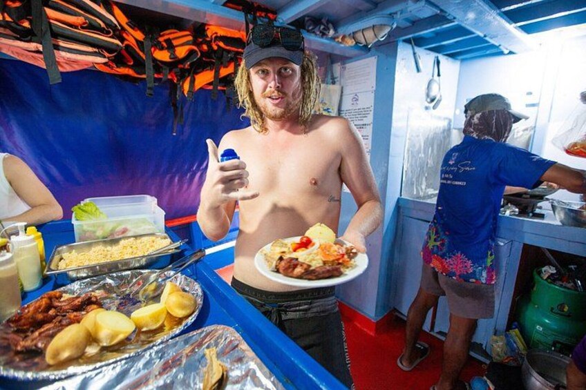 A person holding a plate of food, a grill with food on it, and a person cooking in the background. 5