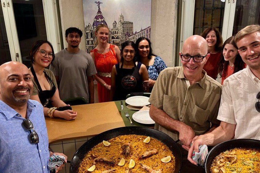 A group of people around a table with large pots of food, likely a communal meal. 3