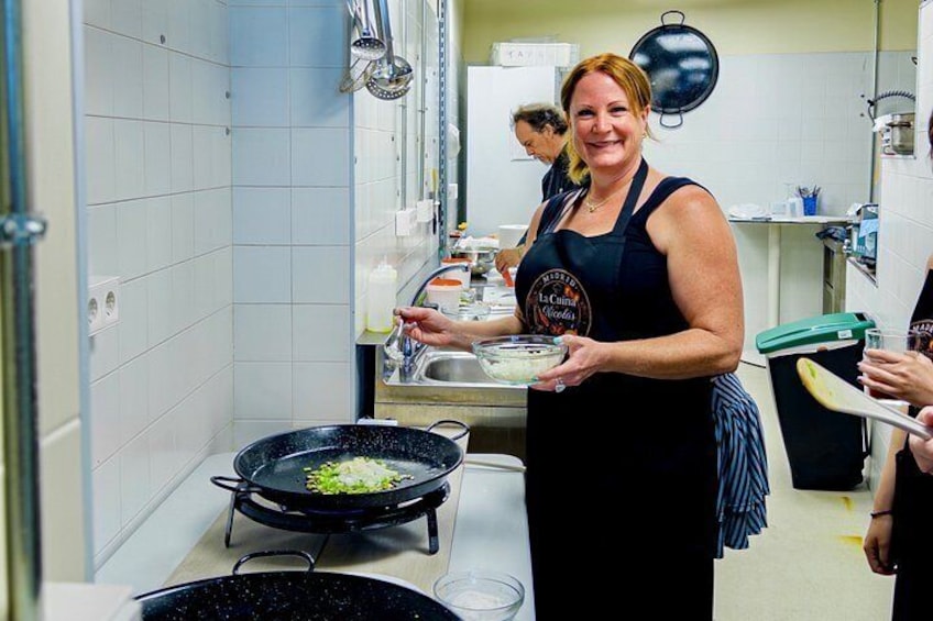 A person in a kitchen holding a tray with food, a stove with a pan, and a sink with dishes. 5