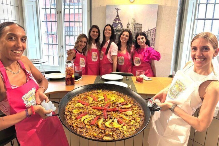 A group of people in aprons around a large pan of paella. 4
