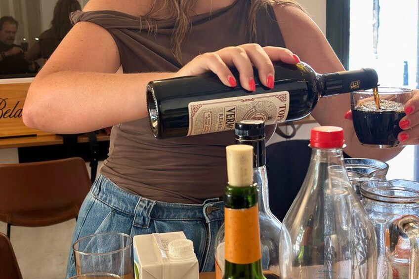 A person pouring a drink from a bottle into a glass. 2