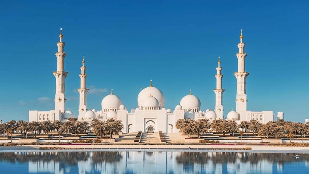 A mosque with multiple domes and minarets, palm trees, and a reflecting pool. 1