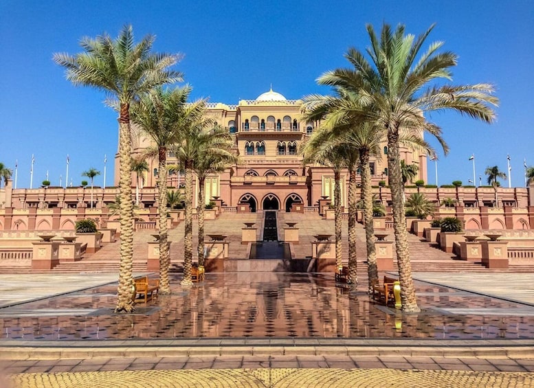 A grand building with a dome, palm trees, and a reflective water feature. 5