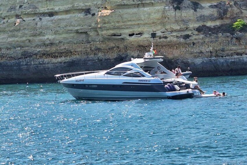 A yacht on calm waters with a rocky cliff in the background. 1