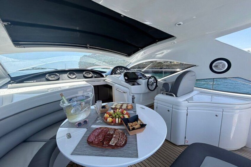 A yacht's interior with a dining table, food, and a view of the sea. 5