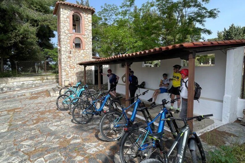 A stone building with a bell tower, a covered seating area, and bicycles parked in front. 2