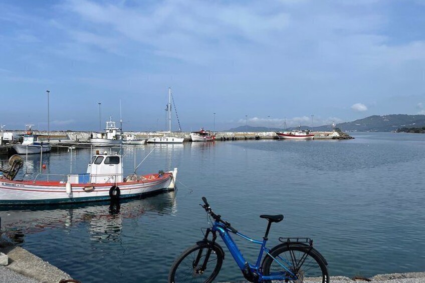 A calm harbor with boats, a bicycle, and a distant shoreline. 3