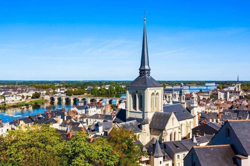 A river, a church with a tall spire, and a bridge in a town. 5