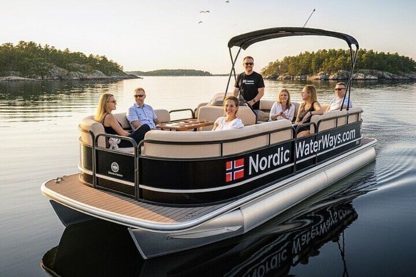 A Nordic WaterWays.com boat with passengers, calm water, and a forested shoreline. 1
