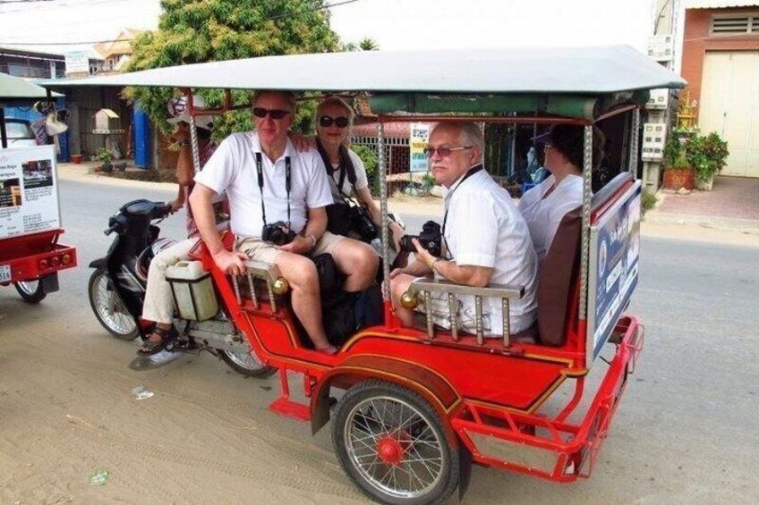 A red rickshaw with passengers, a motorcycle, and a street scene with buildings. 1