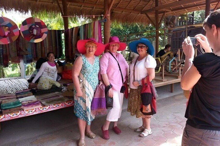 People at a market stall with colorful textiles and hats. 4