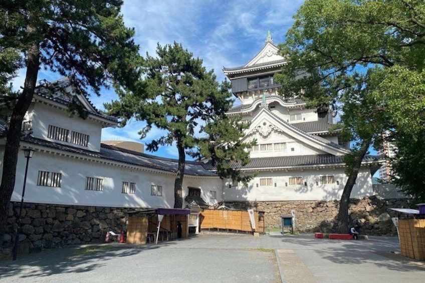 A traditional Japanese castle with white walls and multiple levels, surrounded by trees and a stone wall. 5