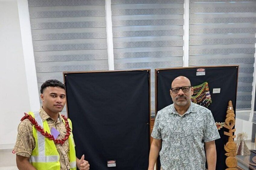 Two individuals standing in front of display panels with black covers, one wearing a safety vest and the other in a patterned shirt. 3