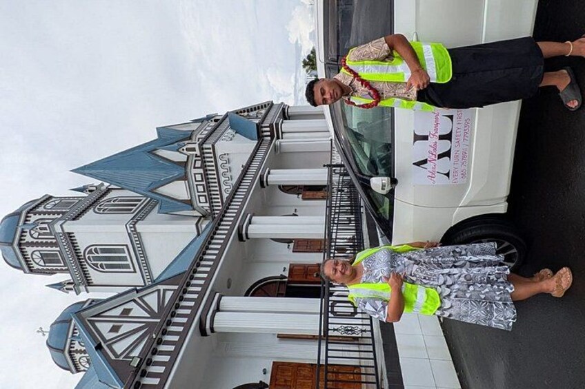 A model ship and two people in reflective vests standing beside a white vehicle. 3
