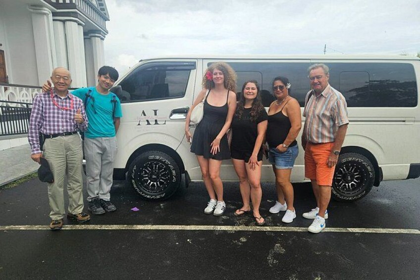 A group of people standing in front of a white van with black wheels. 5