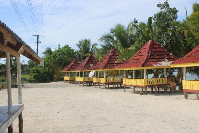 A beach with wooden huts with red roofs and yellow walls. 1