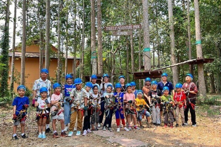 A group of people in a forested area with a sign for 'Treetop Adventure Park.' 4