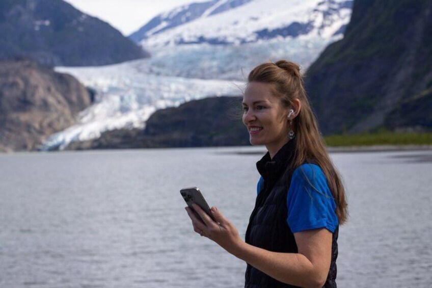 A person standing by a body of water with a glacier in the background. 1