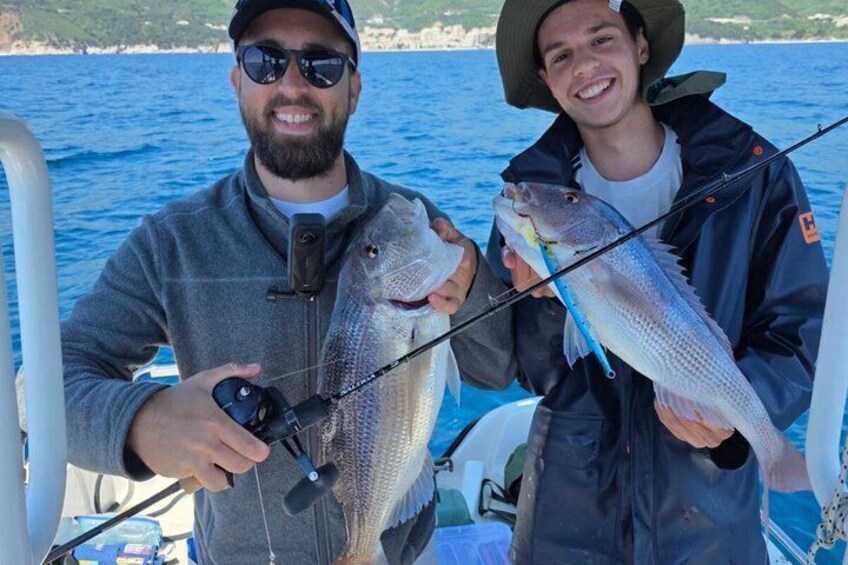 Two people on a boat holding fish. 2