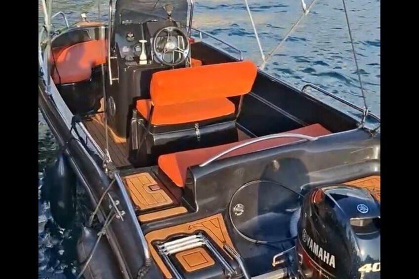 A boat's interior with a Yamaha outboard motor, wooden deck, and orange seating. 1