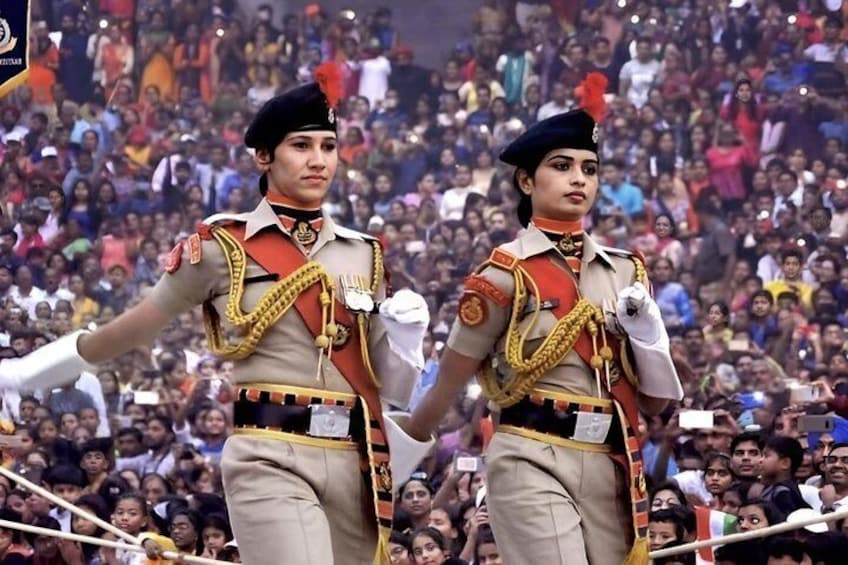 Two individuals in military uniforms with medals, standing in front of a crowd. 5