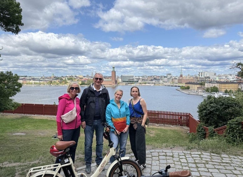 A group of people standing by a river with a cityscape in the background. 2