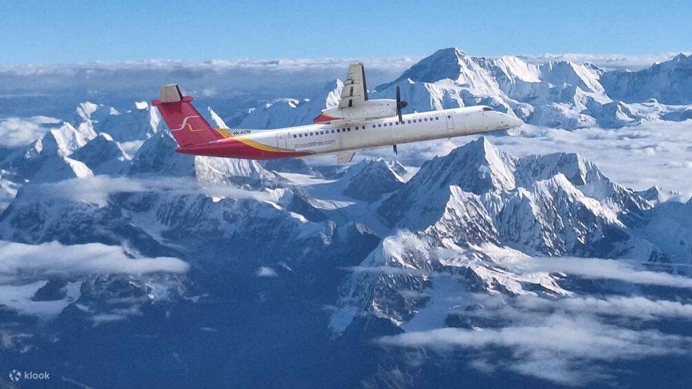 An airplane flying over a mountainous landscape with snow-covered peaks. 1