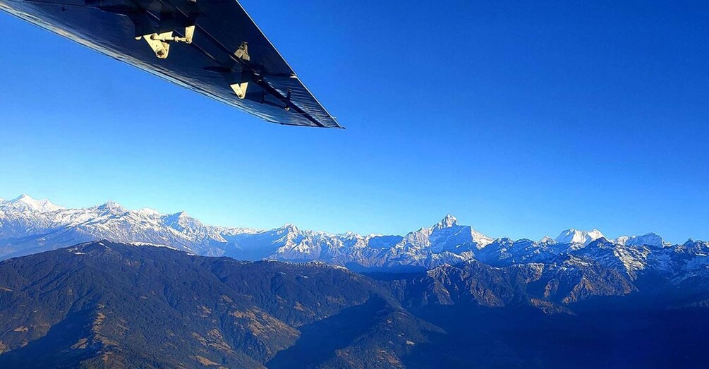 A wing of an aircraft with a mountainous landscape in the background. 3