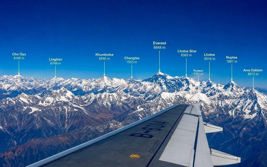 An airplane wing with a view of snow-covered mountains and labeled peaks including Everest, Lhotse, and Ama Dabalam. 1