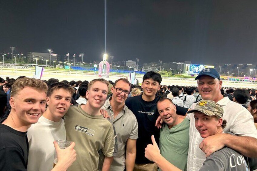 A group of people at a sporting event with a track and field in the background. 1
