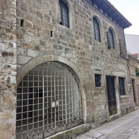 A historic stone building with arched windows and a large metal gate. 5