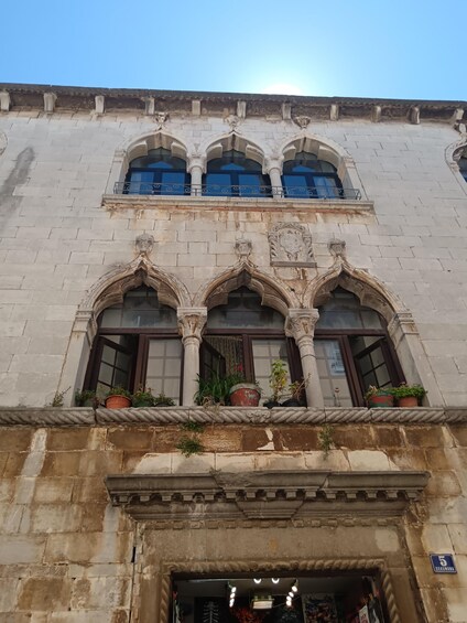 A historic building with ornate windows and a balcony adorned with potted plants. 3