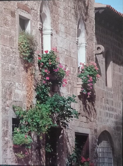 A historic stone building with arched windows and a decorative metal gate. 4