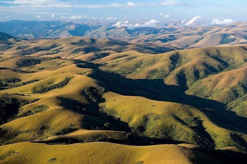 Rolling hills with varying shades of green and brown, suggesting a hilly or mountainous terrain. 3