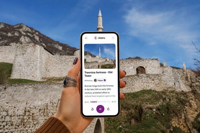 A hand holding a smartphone displaying information about Travinca fortress in Old Town. 1