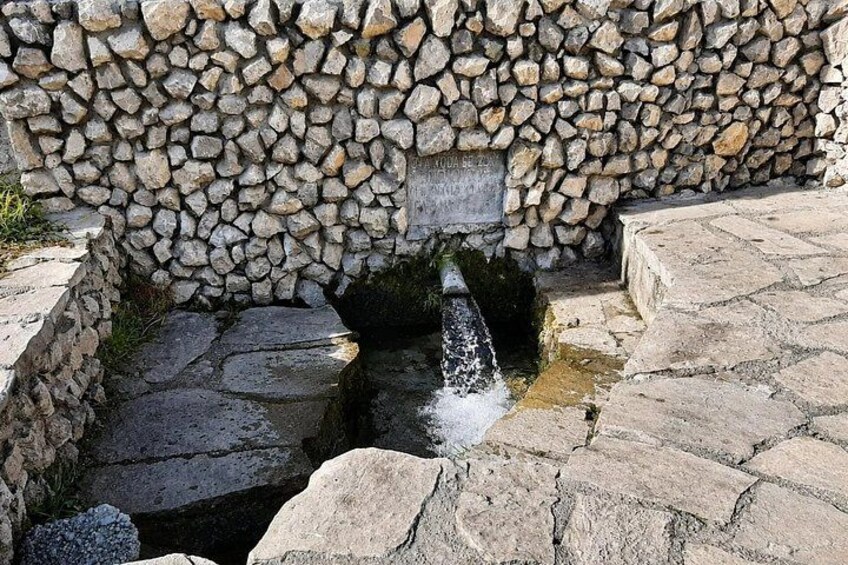 A stone wall with a small waterfall and a plaque. 4
